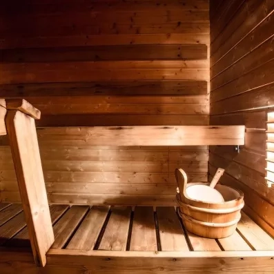 Sauna finlandais traditionnel en bois avec seau et louche pour une séance bien-être au Samperin Savotta.