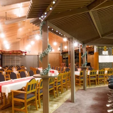 Grande salle de réception conviviale avec tables dressées pour un banquet festif au Samperin Savotta, Finlande.