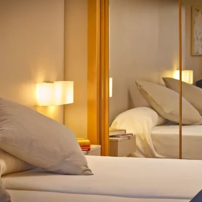 Un gros plan sur un lit confortable, reflété dans un miroir de chambre.