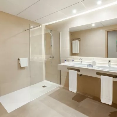 Une salle de bain moderne, dotée d'une grande douche à l'italienne et d'un long plan vasque.