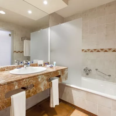 Une salle de bain avec un meuble en marbre brun, une baignoire et un grand miroir.