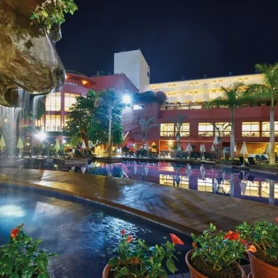 De nuit, on voit les éclairages de l'hôtel et des jardins avec la piscine.