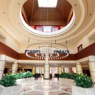 Le hall d'entrée majestueux se distingue par son haut plafond circulaire et ses plantes vertes décoratives.