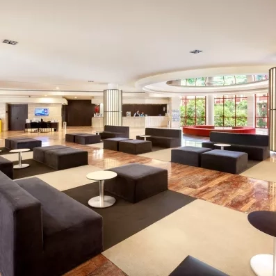 Un vaste espace de réception contemporain présente des canapés sombre.