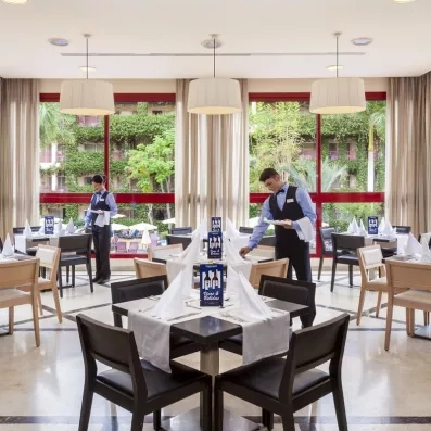 Un restaurant élégant où des serveurs préparent des tables dressées.