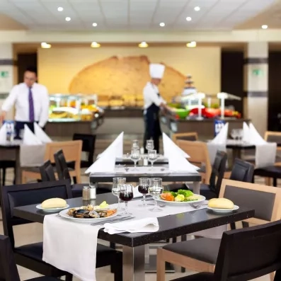 Une salle de restauration spacieuse avec un buffet central et des tables prêtes pour le service.