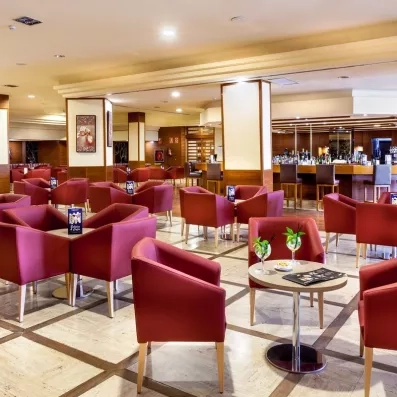 Un salon d'intérieur chic avec de nombreux fauteuils en velours rouge et de petites tables rondes.