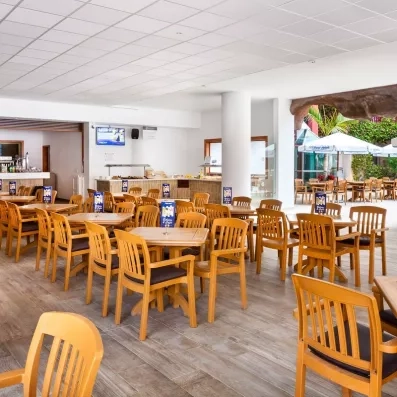 Une salle de snack-bar , équipée de mobilier en bois clair et ouverte sur l'extérieur.