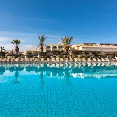 Grande piscine d'eau bleue entourée de transats et palmiers sous le soleil de l'hôtel Djerba Aqua Resort.