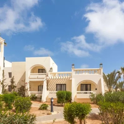 Façade blanche typique et balcons fleuris des chambres de l'hôtel de luxe Djerba Aqua Resort à Djerba.