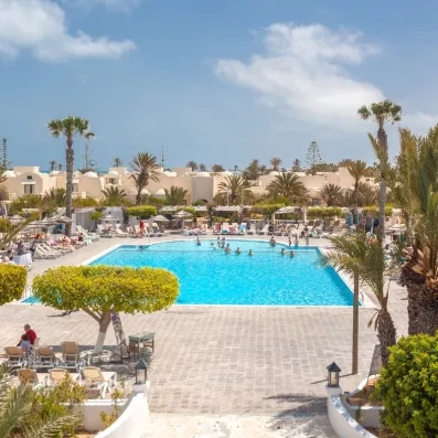 Vue panoramique sur la piscine principale animée et les jardins exotiques du village vacances Djerba Aqua Resort.