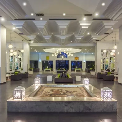Grand lobby moderne du Djerba Aqua Resort avec mosaïque traditionnelle au sol et lustres contemporains élégants.
