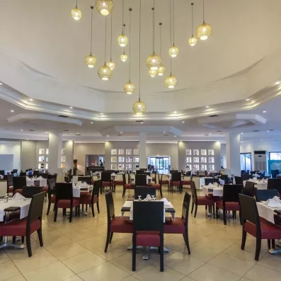 Grande salle de restaurant lumineuse et moderne du Djerba Aqua Resort sous un lustre design doré.