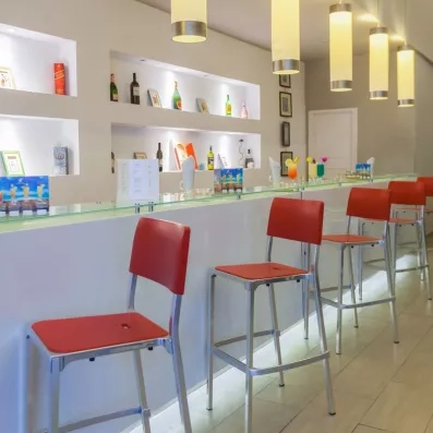 Bar design aux chaises rouges proposant des cocktails colorés pour un séjour détente à Djerba.