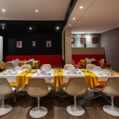 Salle de restaurant thématique aux nappes jaunes et fauteuils rouges pour un dîner convivial en Tunisie.