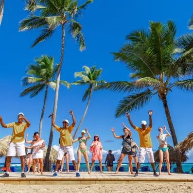 cours de danse ou de gymnastique sur la plage avec des animateurs internationaux sur une plateforme, ciel bleu et palmiers
