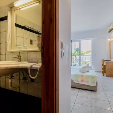 Chambre avec deux lits collés une porte fenêtre de la terrasse et la salle de bain