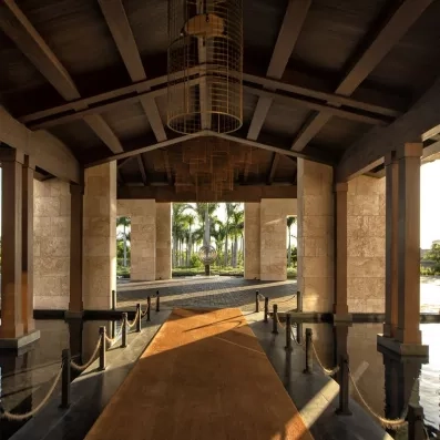 entrée couverte, sculpture cercle devant des rangées de palmiers, long tapis marron menant à l'entrée de l'hôtel