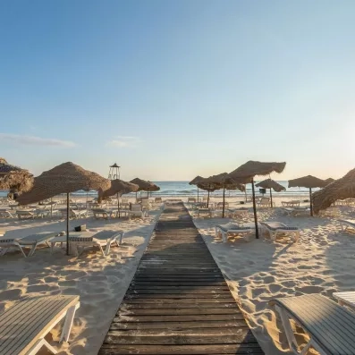 Plage de sable fin et parasols en paille au Marhaba Beach Monastir pour un séjour balnéaire.