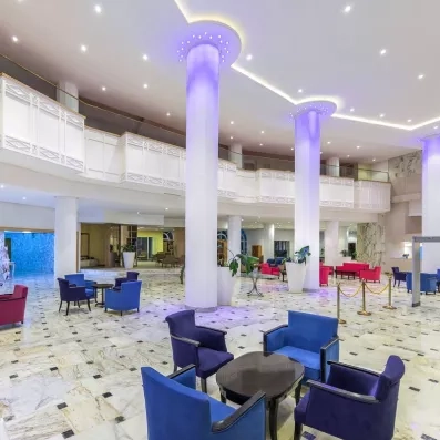 Hall d'entrée moderne du Marhaba Beach Monastir avec colonnes lumineuses bleues et fauteuils colorés confortables.