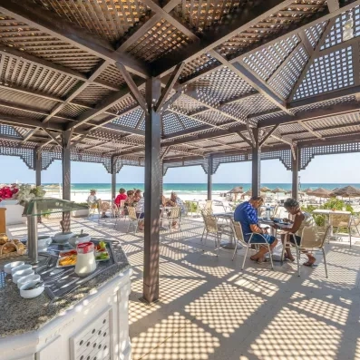 Terrasse ombragée du restaurant de plage offrant une vue panoramique sur la mer Méditerranée à Monastir.
