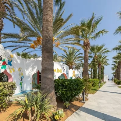 Entrée colorée du club enfant Mini Club entourée de palmiers tropicaux au Marhaba Palace à Monastir.