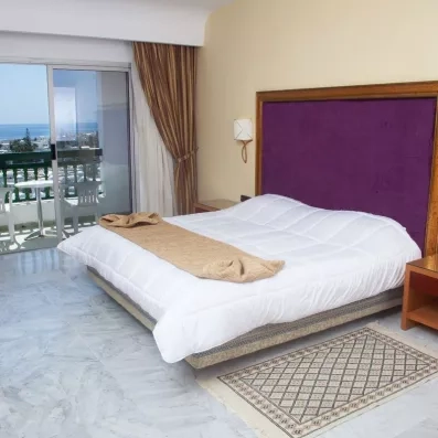 Chambre spacieuse avec lit double, sol en marbre et balcon vue mer au Marhaba Palace à Monastir.