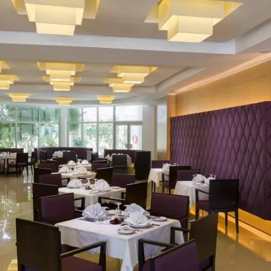 Salle de restaurant élégante avec décoration violette et tables dressées pour un séjour luxe à Monastir.