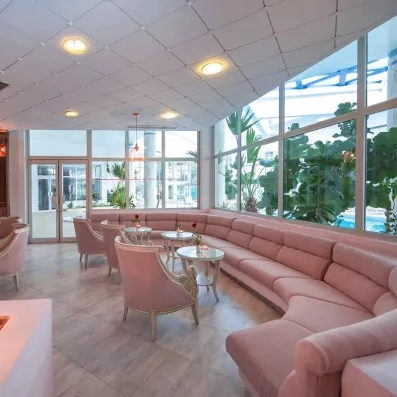 Salon lounge design avec banquettes roses et grandes baies vitrées lumineuses à l'hôtel Marhaba Palace.