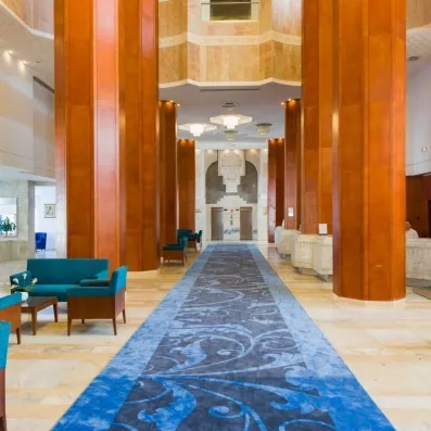 Hall de réception luxueux avec colonnes en bois et tapis bleu au Marhaba Palace à Monastir.