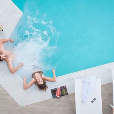 Un couple dans la piscine de l'hôtel profitant du soleil en mangeant des fruits