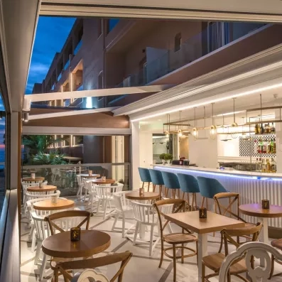 bar de l'hôtel avec des chaises hautes au bord du comptoir et des tables & chaises basses  