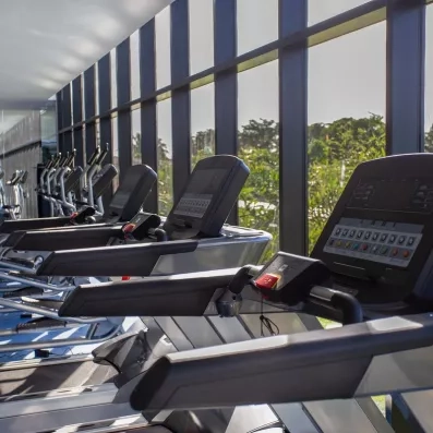 salle de fitness, machines de sport, tapis de course, vue sur l'extérieur, végétation luxuriante