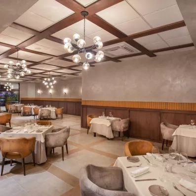 salle de restaurant avec lustres en forme de bulles, nappes blanches, verres à viin, fauteuils en velours gris et marrons