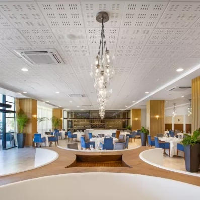 restaurants fauteuils bleus et tables rondes avec nappes blanches, lustres en forme de bulles sur toute la longueur du plafond