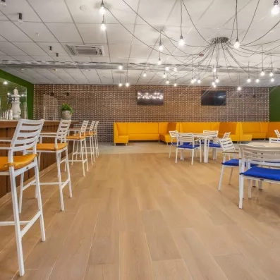 salle de restaurant avec fauteuils en velours gris, tables carrées avec nappe blanche