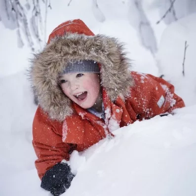 Enfant s'amusant dans la neige lors d'un voyage familial hivernal au Samperin Savotta en Laponie.