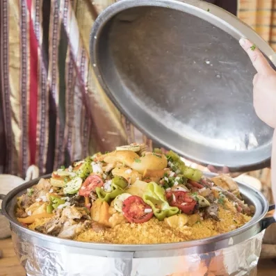 Gros plan sur un généreux plat de couscous royal tunisien garni de légumes grillés, tomates et viandes, servi au buffet du restaurant.