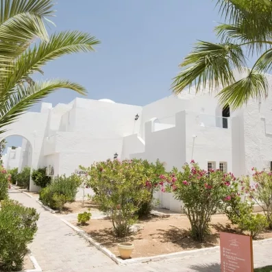 Allée piétonne du Seabel Aladin bordée de lauriers roses et de bâtiments à l'architecture tunisienne blanche.