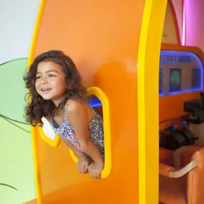 Enfant souriante jouant dans l'espace cockpit ludique du mini club Mondi Club Seabel Aladin à Djerba.