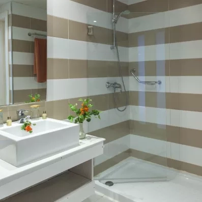 Salle de bain moderne avec douche à l’italienne, vasque design et décoration florale.