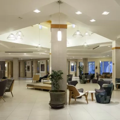 Lobby d’hôtel spacieux avec fauteuils contemporains, éclairage design et colonnes décoratives.”