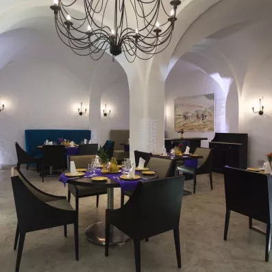 Restaurant élégant avec tables dressées, vaisselle dorée, lustre artistique et ambiance raffinée.
