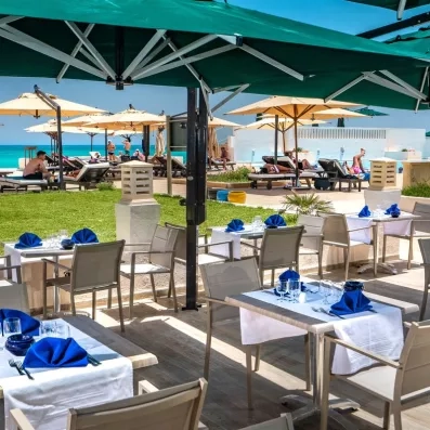 Terrasse ombragée du restaurant de l'hôtel Ulysse à Djerba avec vue sur mer et plage paradisiaque.