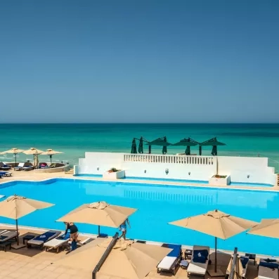 Vue panoramique sur la piscine turquoise et la mer Méditerranée depuis l'hôtel Ulysse à Djerba, Tunisie.