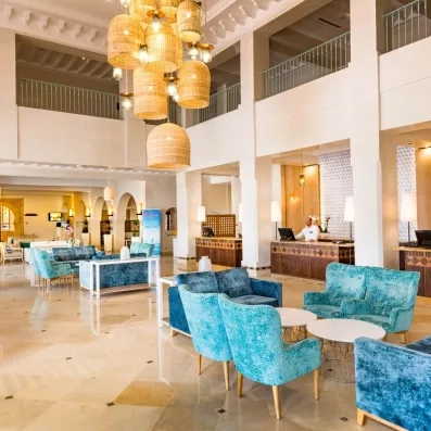 Lobby luxueux de l'hôtel Ulysse à Djerba avec lustres en osier et fauteuils bleus au design moderne.