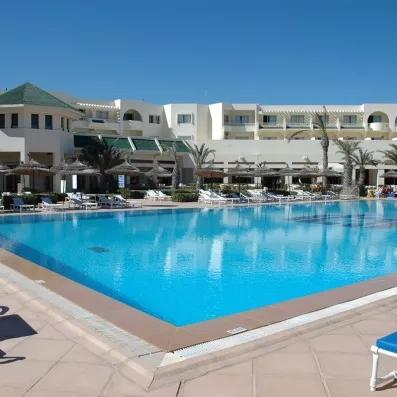 Grande piscine extérieure ensoleillée entourée de parasols et transats à l'hôtel Vincci Dar Midoun, Djerba.