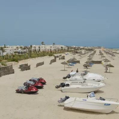 Panorama de la plage privée avec bateaux et jet-skis au pied de l'hôtel Helios Beach.