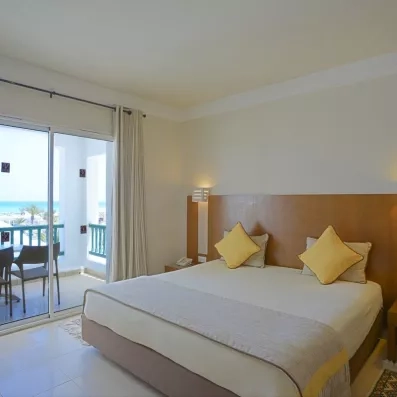 Suite spacieuse et élégante à l'hôtel Helios Beach avec coin salon, grand lit et décoration tunisienne moderne.