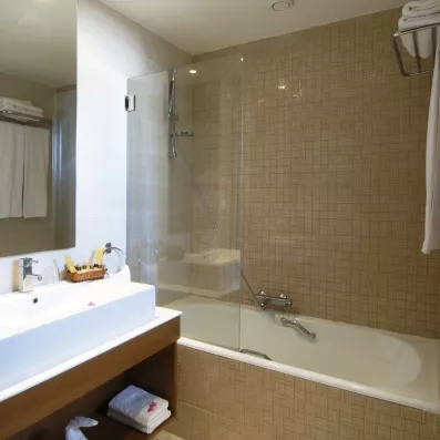 Salle de bain moderne de l'hôtel Helios Beach à Djerba équipée d'une baignoire et de produits d'accueil.